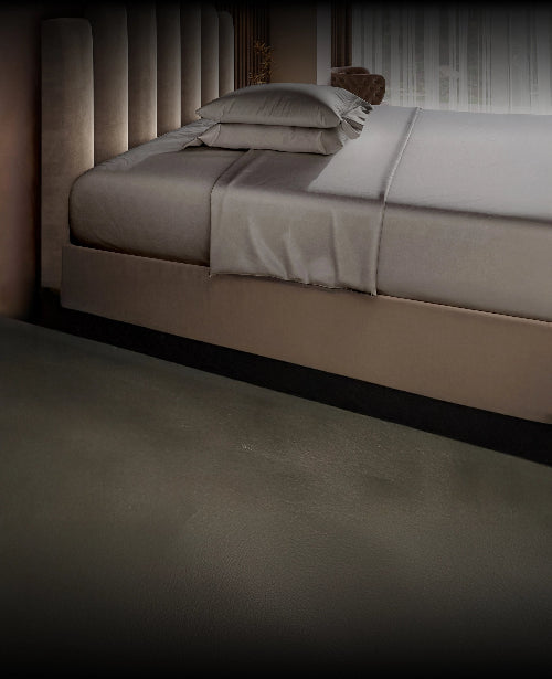 Gray bed with gray Puffy bedding in a dimly lit room