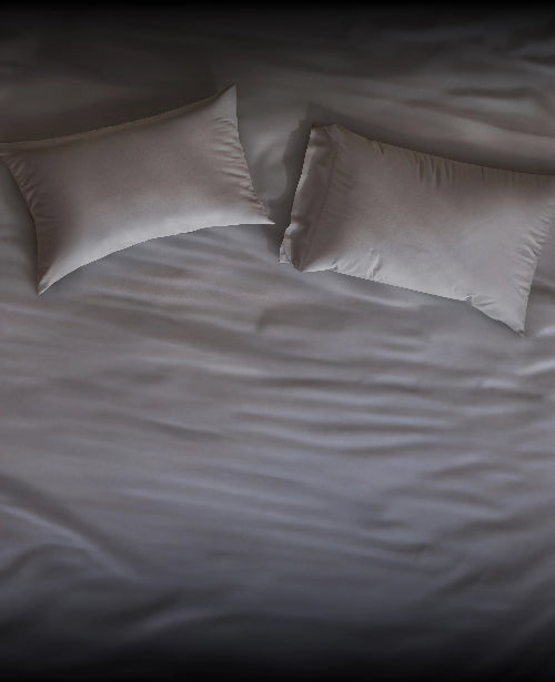 Two gray Puffy pillows on a white bedspread