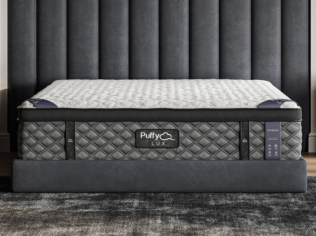 A hybrid mattress by Puffy Lux, shown in a bedroom setting, featuring a quilted pattern on the surface from Factory Direct Mattress KCK