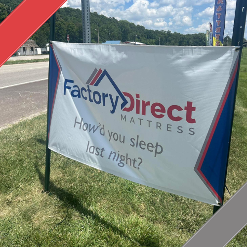 Factory Direct Mattress KCK promotional banner on grass with road and trees in the background