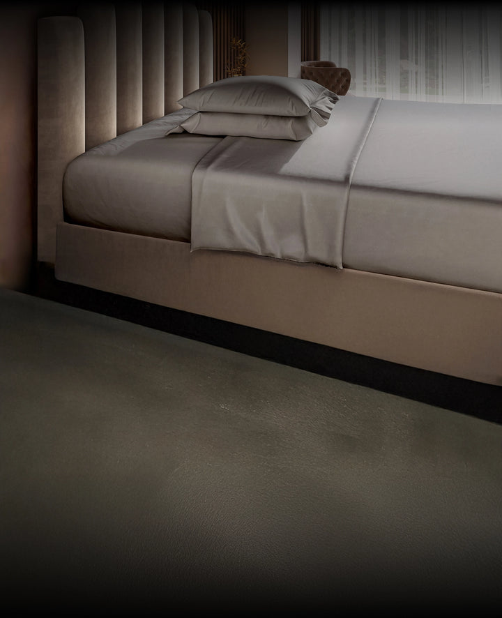Gray bed with gray Puffy bedding in a dimly lit room