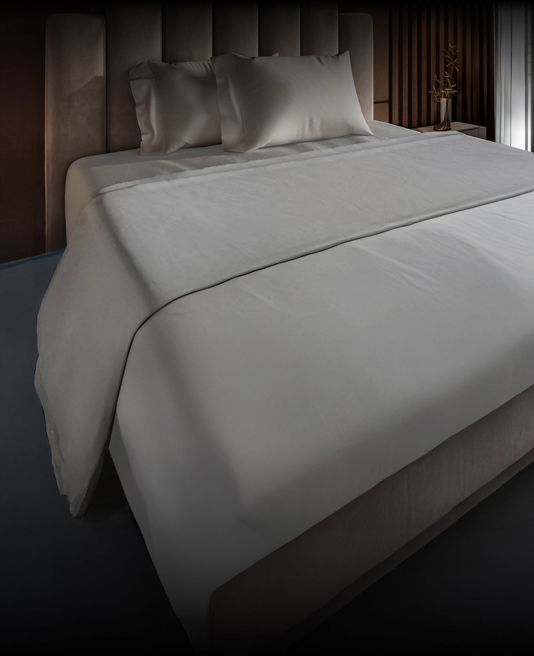 Gray bedspread on a Puffy mattress with pillows in a bedroom setting