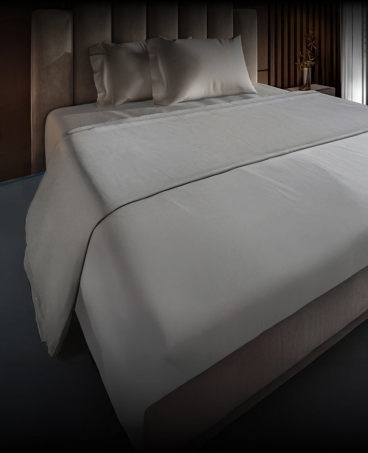 Gray bedspread on a Puffy mattress with pillows in a bedroom setting