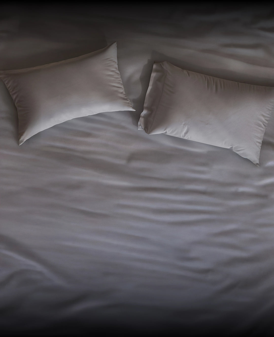 Two gray Puffy pillows on a white bedspread